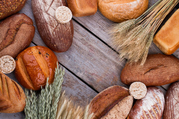 Bread on vintage wooden background. Baked bread and wheat ears. Space for text.