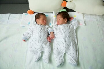 Cute twin baby asian boys sleeping together.