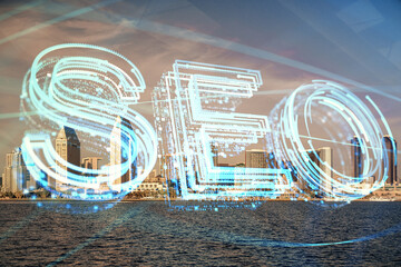 SEO hologram on city view with skyscrapers background double exposure. Search optimization concept.