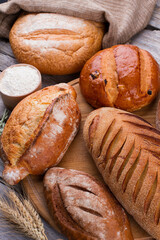 Assortment of baked bread on wooden background. Fresh homemade bread on rustic wooden table.