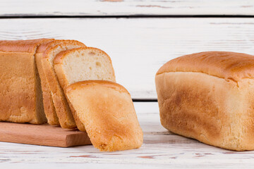 Organic white toast bread. Sliced and whole bread loaves on wooden background.