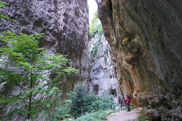 people walking between high rocks on a riverbed