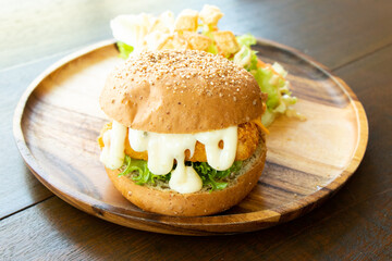Fried fish fillet burger with vegetable salad on wood plate background