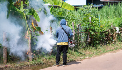 Worker fogging machine spraying smoke to eliminate mosquitoes.