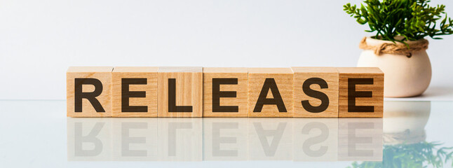 Release message word on a wooden desk on cube blocks with a flower on background