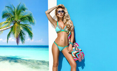 Elegant sexy woman in the colorful bikini on the sun-tanned slim and shapely body is posing near...
