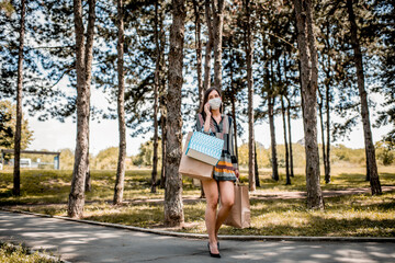 Woman with face mask walking down the street using phone