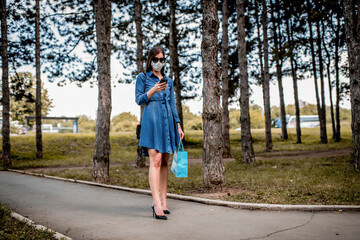 Woman with face mask walking down the street using phone