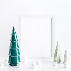 Christmas mockup frame with ceramic Christmas trees and white baubles on white background. Minimalistic Christmas card with modern decor, copy space, square format