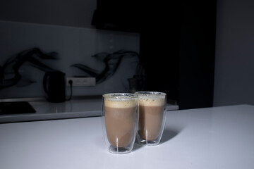 two cups of coffee in double-botoom glass on white table in gray kitchen. High quality photo