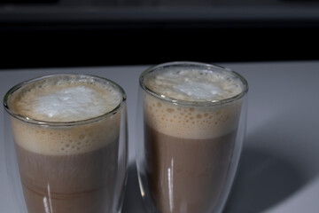 two cups of coffee in double-botoom glass on white table in gray kitchen. High quality photo