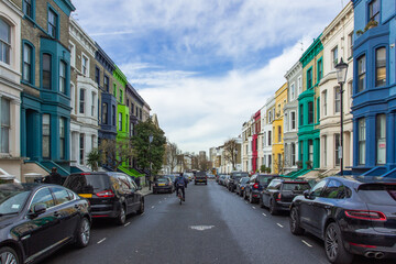 Residential street with colorful houses in Notting Hill, London, UK. Typical English houses facades in blue, pink, yellow and white colors. British pastel buildings.Real estate concept urban scene