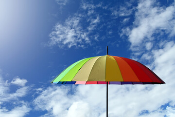 Colorful umbrella multicolored on a blue sky background