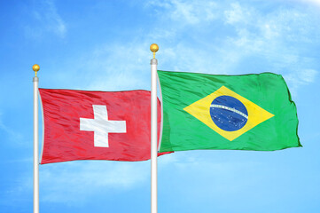 Switzerland and Brazil two flags on flagpoles and blue sky