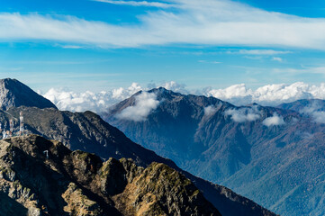 Sochi, Rosa hutor.  The mountain landscape on a sunny automn day. The clouds resting on mountain peak. On photo we can see avalanche equipment on the edge of rocks