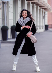 Brunette model makes funny dancing movement at the city