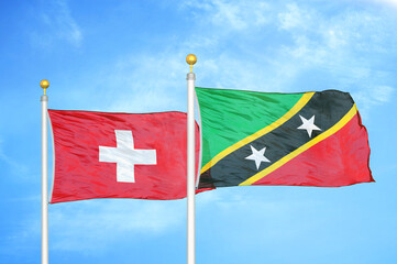 Switzerland and Saint Kitts and Nevis two flags on flagpoles and blue sky