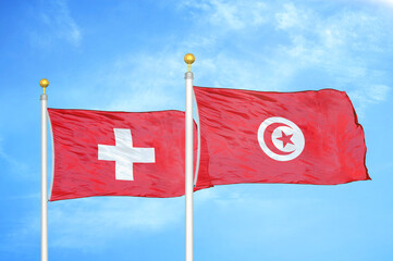 Switzerland and Tunisia two flags on flagpoles and blue sky