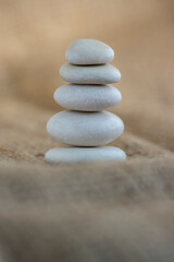 Fototapeta na wymiar One simplicity stones cairn on jute brown background, group of five light gray pebbles built in tower