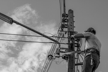Electricians working on power pole connecting cables with clear sky background.- Concept of...