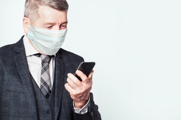 Senior man in medical protective face mask using smart phone isolated on white