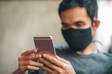 Close up hand holding mobile smartphone,man a wearing face mask in cafe