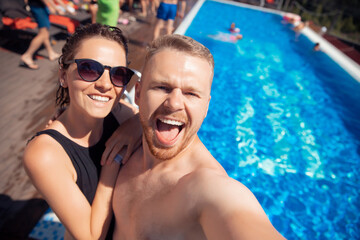 Cheerful happy couple guy and woman make selfie photo in hotel pool, summer vacation travel