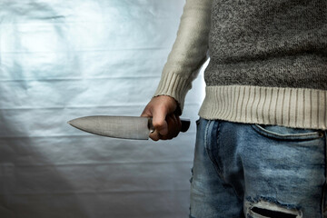 An evil man holds a shiny steel knife in his hand, a killer in action. A maniac is hunting a victim.