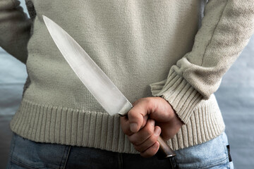 An evil man holds a knife behind his back, waiting for the victim. A maniac and a rapist with a gun.