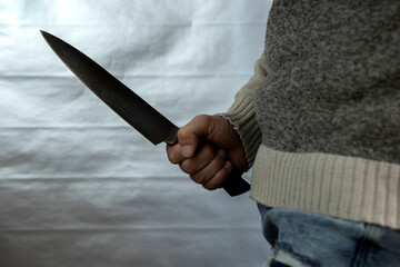 An evil man holds a shiny steel knife in his hand, a killer in action. A maniac is hunting a victim.