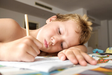 Detail of a tired and boring boy in summer while I finish his homework writing something repeated in his notebook.