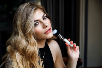 Obraz premium Close up portrait makeup artist. Make up courses. Woman hold makeup brushes on the hands.