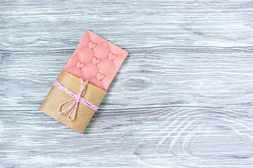 Pink chocolate whole bar decorated with slices of fruit nuts and slices against gray background. Trendy handmade chocolate. Gift Idea.