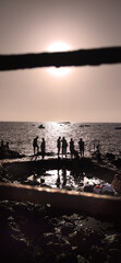 19:9 Format, Beach day with people talking and enjoying the sunny day, rocks, in sunset, volcano beach in Tenerife. 