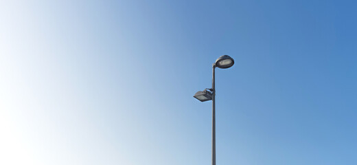 Wide format, Street light metal pole with two lamp on it, blue background , minimalist. 