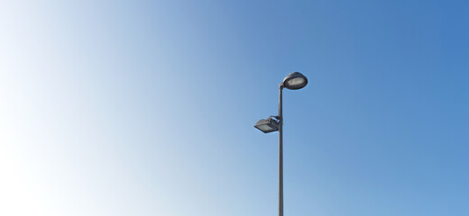 Wide format, Street light metal pole with two lamp on it, blue background , minimalist. 