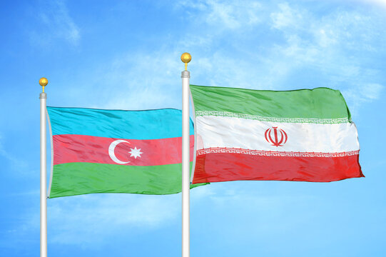 Azerbaijan and Iran two flags on flagpoles and blue sky