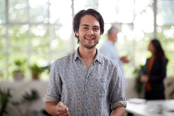 Young professional man standing in an open plan office