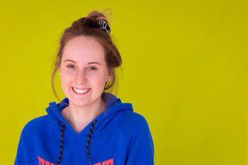 head and shoulders of teenage girl in blue hoody against plain green background