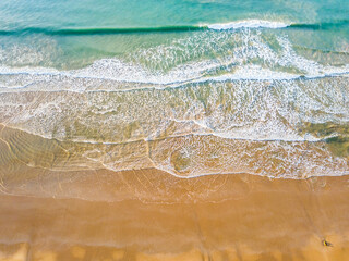 Looking down on gentle waves breaking on a sandy beach