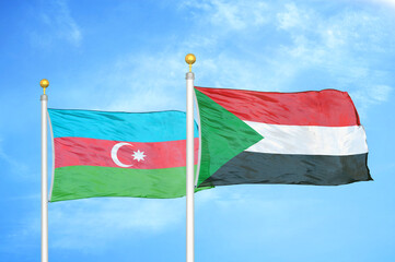 Azerbaijan and Sudan two flags on flagpoles and blue sky