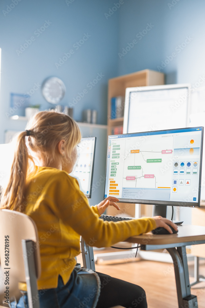 Wall mural elementary school computer science classroom: cute little girl uses computer, learning programming l