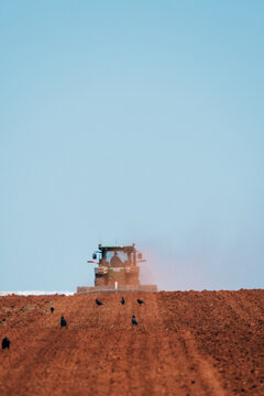 Tractor plowing red dirt for cropping.