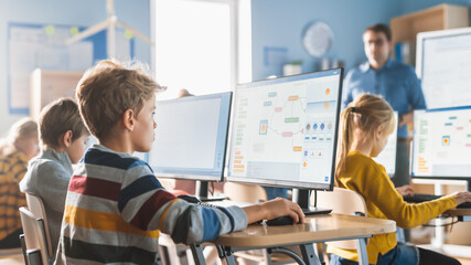 Elementary School Computer Science Classroom: Smart Little Schoolboy Work on Personal Computers,...