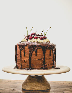 Chocolate black forrest cake with drip and fresh red cherries.