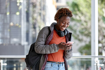African woman having fun in city checking mobile phone