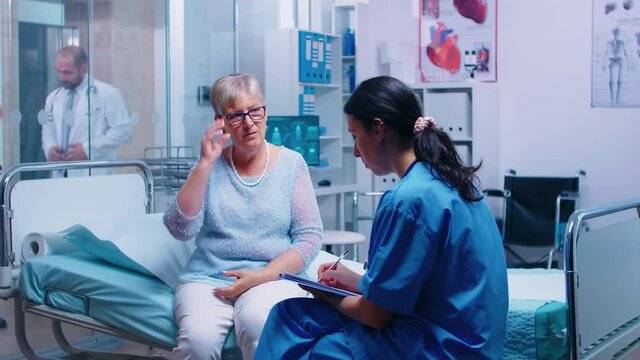 Old redired senior patient answering nurse questions before doctor appointment in modern private healthcare facility. Converstation with medical stuff hospital clinic medicine healthcare