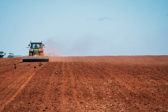 Tractor plows red dirt ready for cropping.