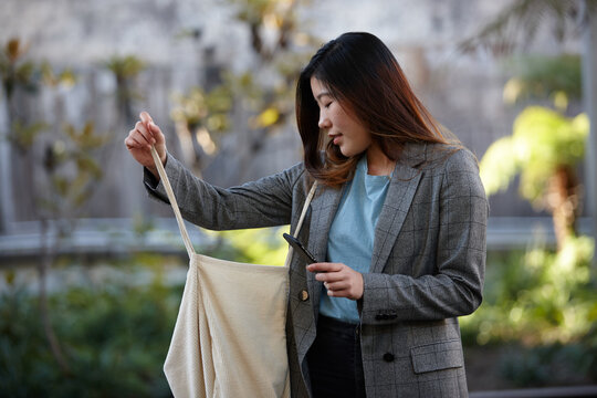 Young Asian woman holding shopping bag outdoors at enclave