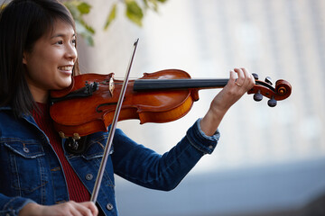 Young Asian female violin player practising outdoors